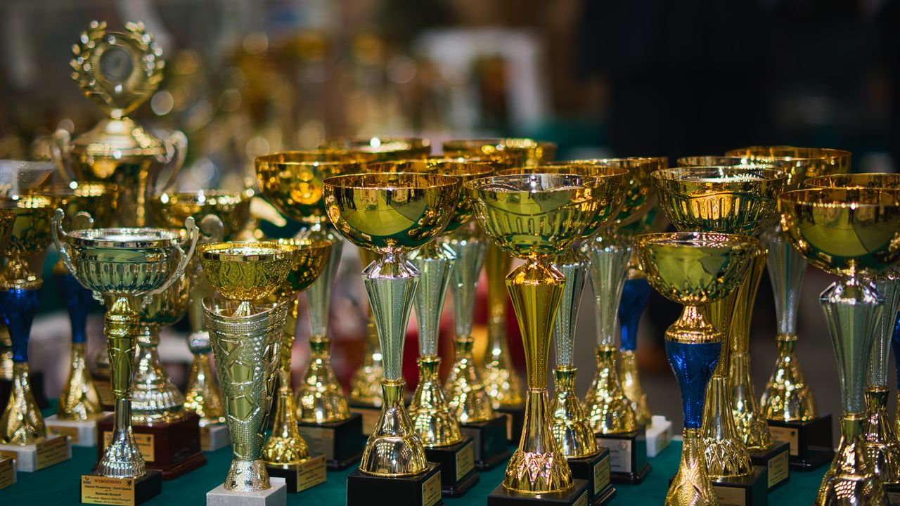 about-02 Array of golden trophies on a table, reflecting victory and achievement.