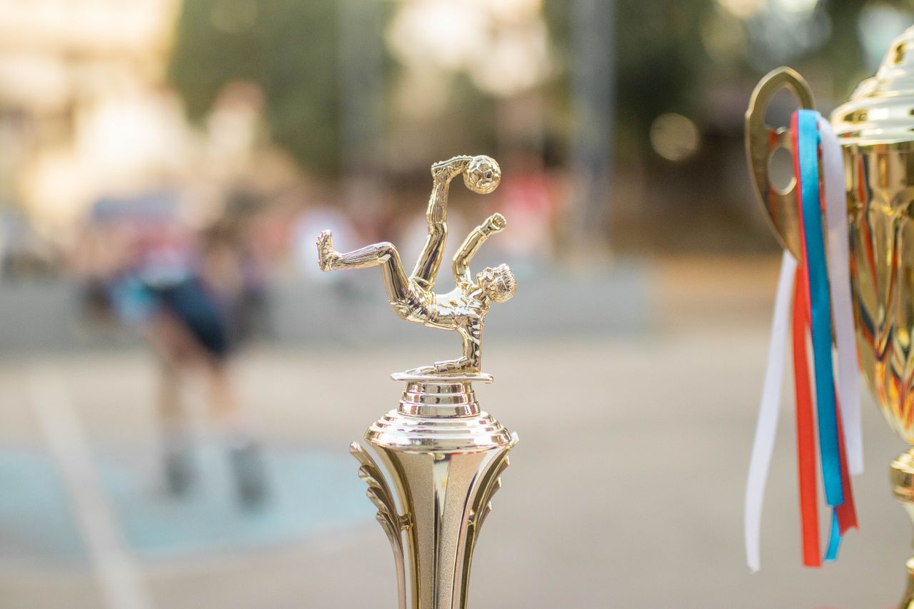 The Art of Drawing Readers In: Your attractive post title goes here Golden football trophy with ribbons on display, capturing the essence of victory and sportsmanship.