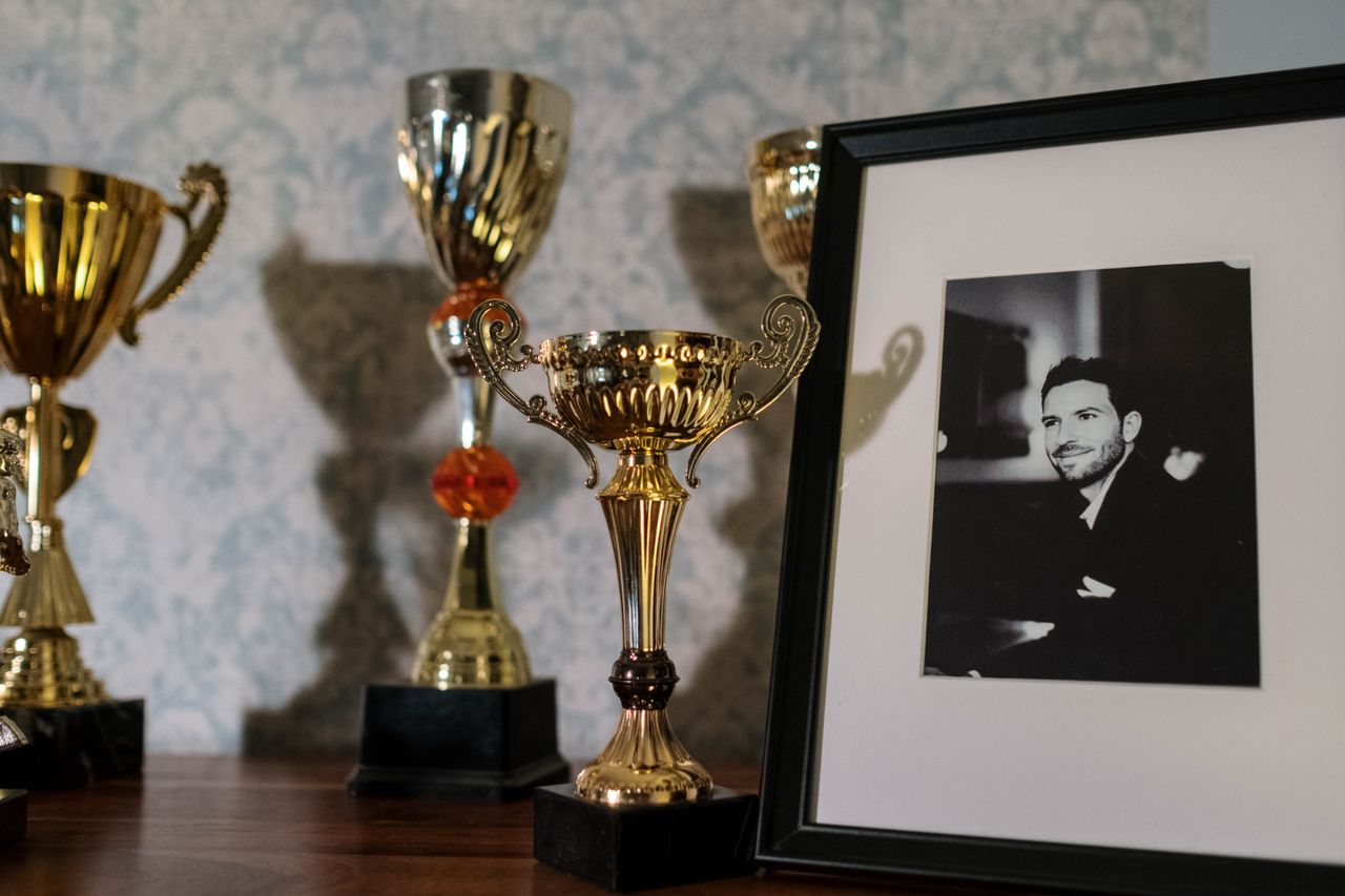 Mastering the First Impression: Your intriguing post title goes here A collection of trophies with a framed black and white portrait on a shelf.