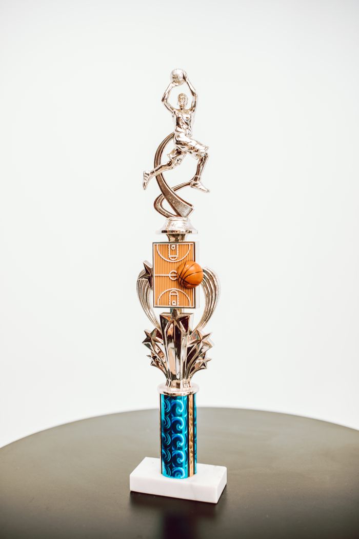 services-01 A silver basketball trophy with intricate design displayed on a round table.